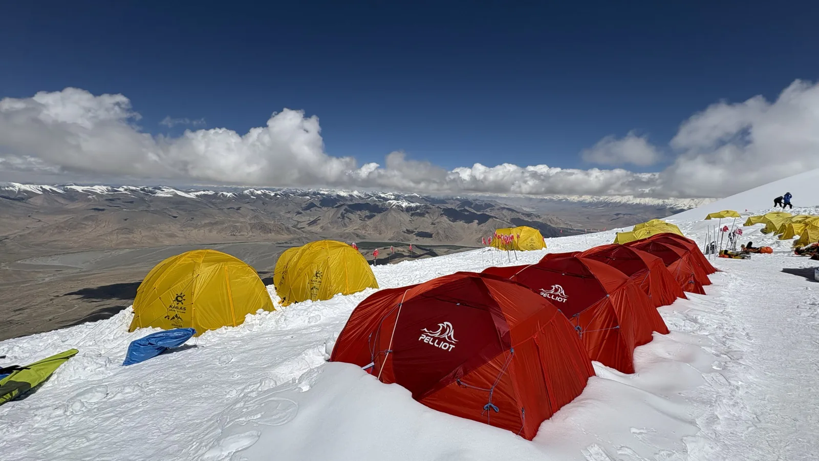 Red and yellow high-altitude tents overlooking the broad Pamir landscape.