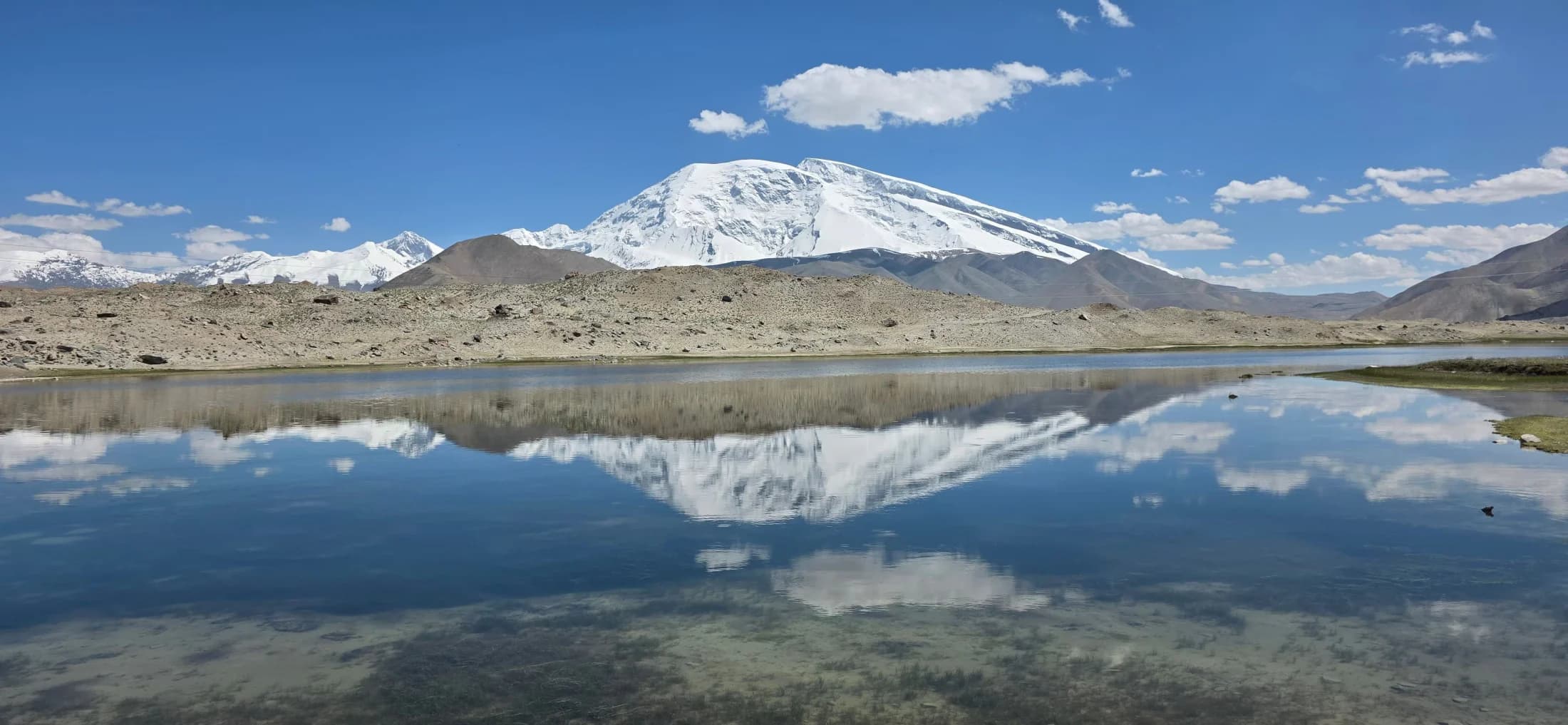 A high Pamir mountain reflected beside an overland approach