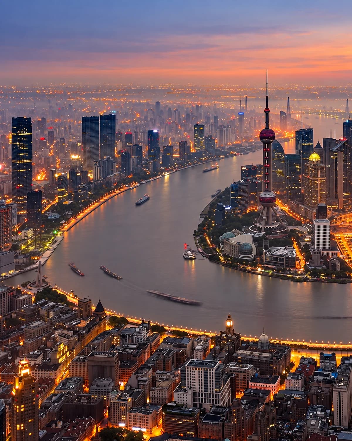 The Huangpu River curving between the Bund and the illuminated Lujiazui skyline.