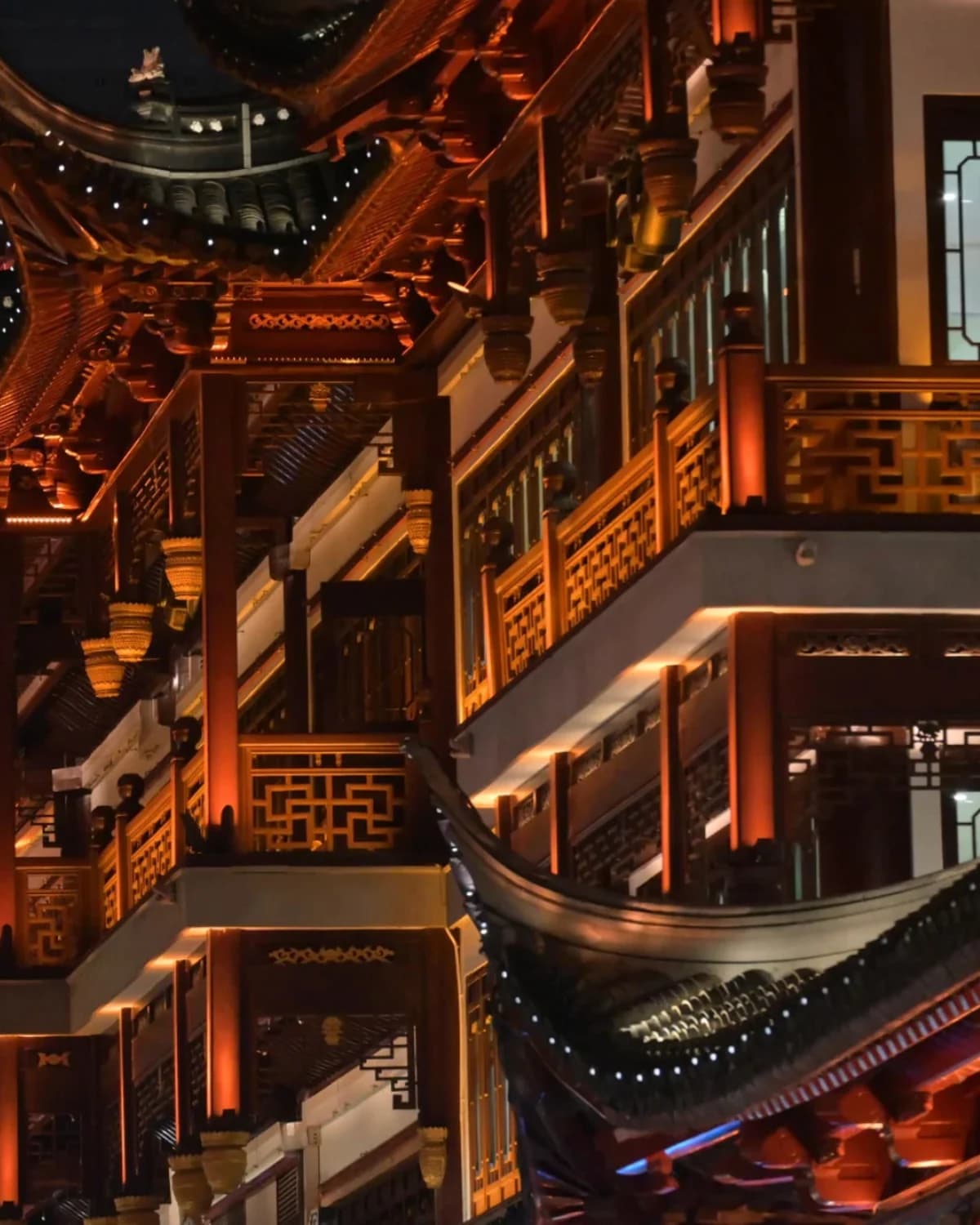 Vertical night view of carved balconies and traditional rooflines near Yu Garden.
