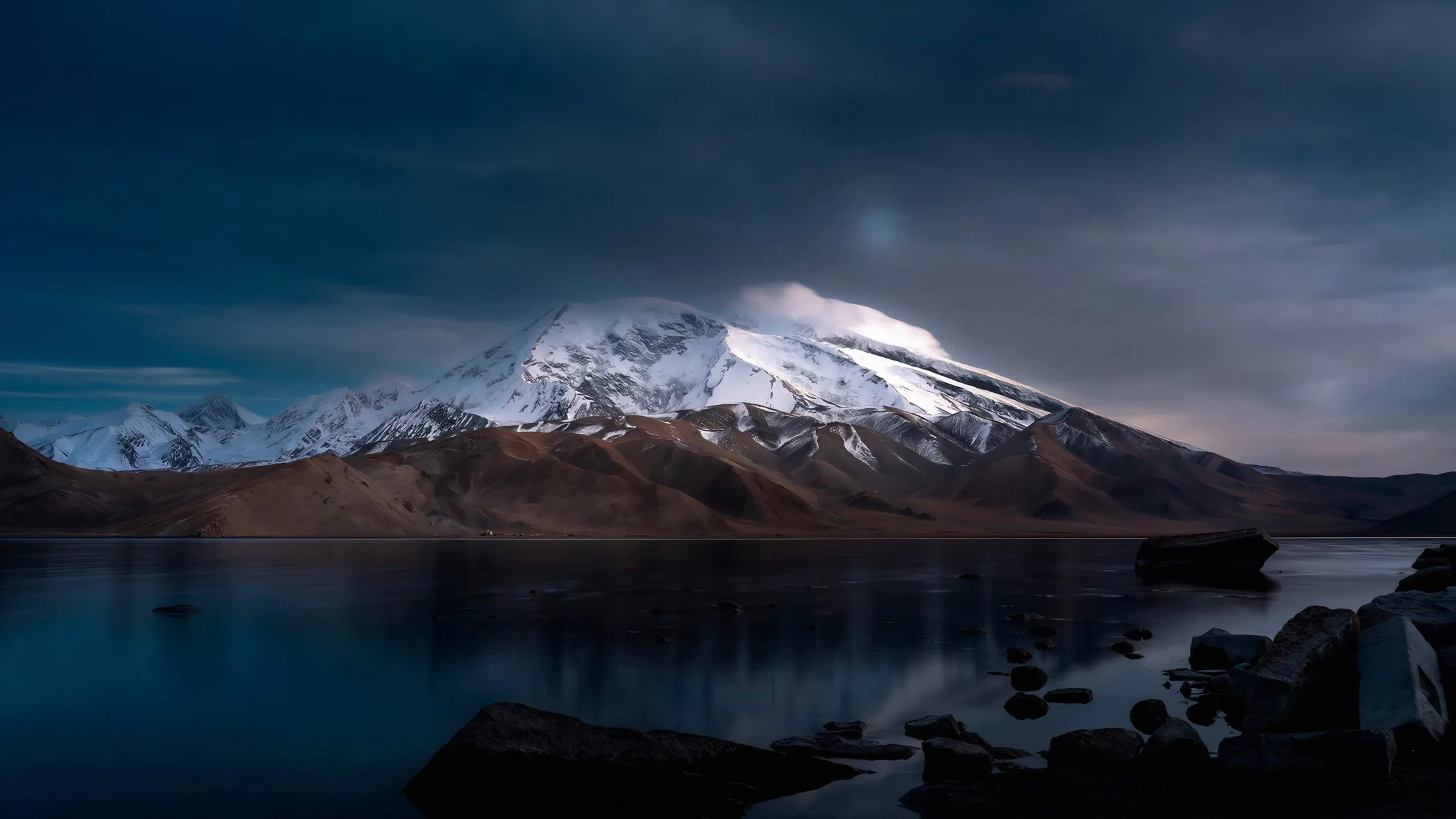 Muztagh Ata above a dark lakeshore after dusk